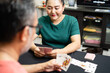 Couples playing cards at home for date night inside. They both held cards in their hands and smiled happily. The concept for a game on, love, enjoy, happy. Closeup, blurred background, selective focus
