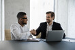 © fizkes - Happy multiethnic customer and manager finishing meeting with handshake. Business men shaking hands after negotiation, closing deal, contract, agreement in office. Client thanking advisor