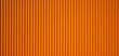 texture of an orange corrugated sheet metal facade. Close up of an exterior wall of a warehouse in the industrial area.
