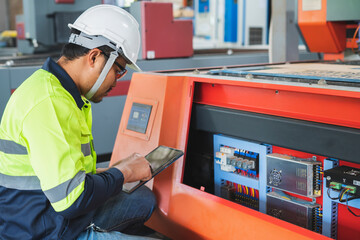 The factory's electrical engineers wear green protective clothing and plastic caps. Use laptops and tablets to check the quality of industrial equipment.
