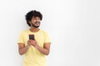 © kucherav - Handsome man Indian man with curly hair and beard in yellow t-shirt sending a message with the mobile. Communicating in social networks, chatting, online shopping concept