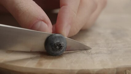 Wall Mural - Slow motion man cut blueberry on olive wood board