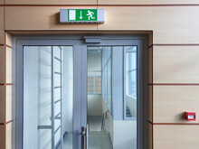 Emergency Exit With Glass Door In Airport Office Building. Emergency Fire Doors. Rescue Signs Icon Green Emergency Exit Lamp