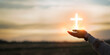 © Yingyaipumi - christian religion and Resurrection concept.woman hands holding worship of cross,hope and faith,eucharist therapy bless god helping on sunset background.