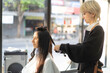 © Siam Stock - Blond Asian female hairdresser in apron making curly hair with curling iron to Caucasian female client in white haircut cape sitting on hairdressing chair smiling looking in a mirror in a beauty salon