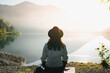Young woman hiker with hat and denim jacket meditating yoga alone at sunrise mountains. View from behind. Travel Lifestyle spiritual relaxation concept. Harmony with nature.