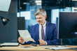 © Liubomir - Successful experienced business man, received a positive letter, a happy message from the bank, the boss works in a modern office, celebrates victory
