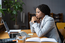 Serious African American Businesswoman Sitting At Table Looking At Laptop Screen. Ethnic Woman Read Message Email With Important News, Business Documents Online, Chatting With Clients Working Remotely