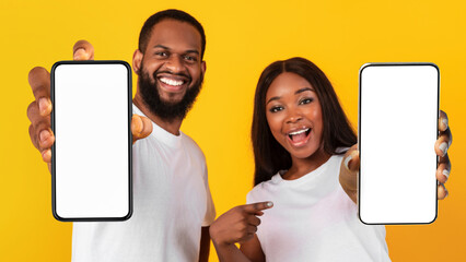 Poster - Black couple showing two blank empty smartphones screen for mockup