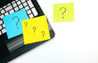 Laptop and memo pieces of paper with drawn question marks on white background. Top view
