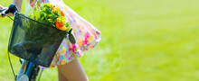 A Young Woman In A Colorful Dress Stands Next To A Bicycle On A Green Lawn With A Bouquet Of Flowers In A Basket Panoramic Photo