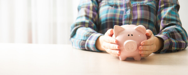 Wall Mural - woman hand putting money coin into piggy for saving money wealth and financial concept