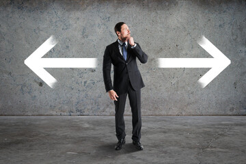 Poster - Thoughtful young businessman standing on abstract concrete background with two arrows. Different direction and choice concept.