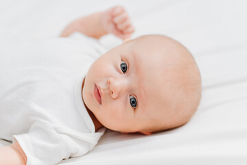 Wall Mural -  cute baby wearing a white t-shirt on a white sheet. pediatrics