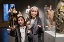 Friendly Elderly Female Tutor Showing Interested Tween Girl Exposition Of Artworks In Museum Of Archeology And Ancient Sculptures