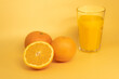 Fresh orange juice with two and half oranges on orange background
