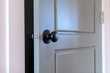 Gray paneled hinged wooden bedroom door with black door knob and visible latch