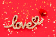 © Laima Gri - Red paper heart and golden word LOVE on a bright red background. Valentines Day concept