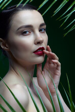 Romantic Female On A Background Of Palm Leaves On Green. Hand Is Near The Face.