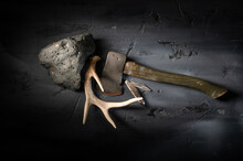 Rugged Stone Rock With Vintage Camping Hatchet Axe And Deer Antler On Textured Dark Gray Surface.