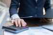 © Pichsakul - Businessman concept the male accountant using the calculator to check the correctness of the numerical data in the info chart on the wooden table