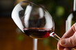 Wine tasting. A glass of red wine on the background of a restaurant table with bottle at an evening dinner or event party.