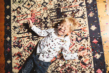 Cheerful Boy Lying On Floor Covered With Confetti
