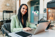 Smiling Businesswoman With Laptop In Cafe