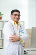 © DragonImages - Portrait of positive mature doctor in white labcoat crossing arms and smiling at camera