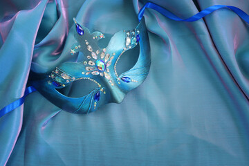 Photo of elegant and delicate Venetian mask over blue silk background