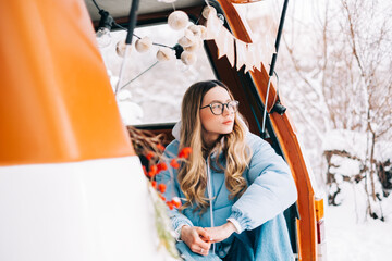 Wall Mural - Portrait of young caucasian happy woman sitting in a car in winter day, during traveling on a van and enjoying holiday.