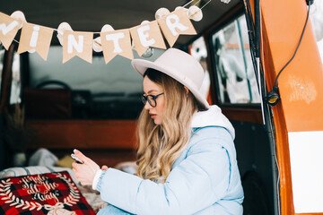 Wall Mural - Young caucasian woman using mobile phone, sitting in a car while traveling in road trip.