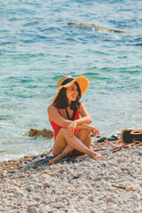 Wall Mural - young pretty woman in straw hat at sea beach