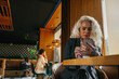 © bernardbodo - Focused businesswoman using phone at cafe