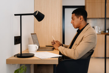 Canvas Print - Black man wearing jacket working on laptop while sitting at desk