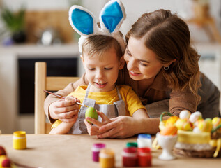 Wall Mural - Delighted woman and boy painting Easter eggs together