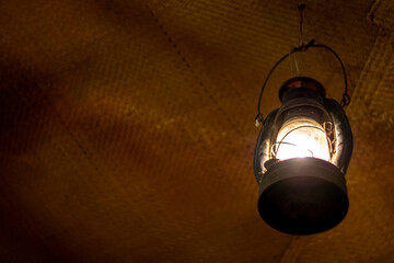 Bright light in an ancient lantern hanging in an old room