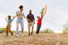 Black Family Laughing And Flying Kite While Running Together