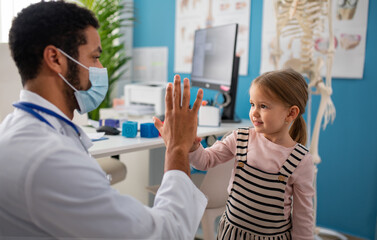 Wall Mural - little girl at doctor's office on, high fiving with doctor.