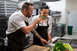 © Halfpoint - Chef giving herbs to smell to his colleague in commercial kitchen.