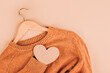 Wooden hangers with sweater on beige background with copy space. Clothing donations, conscious and environmentally friendly consupmtion - new trends in shopping. Slow fashion concept