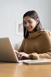 © opolja - Smiling woman with laptop in home office.