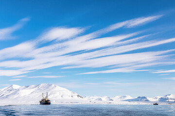 Wall Mural - boat on the fjords of svalbard with snowy mountains and blue sky.
