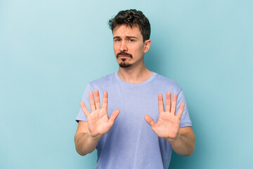 Young caucasian man isolated on blue background rejecting someone showing a gesture of disgust.