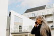 © Johnér - Senior woman talking on cell phone in front of building