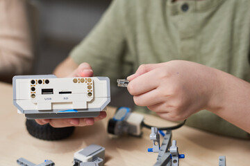 Wall Mural - Close up of unrecognizable boy connecting cables to control module while building robot in engineering class at school, copy space