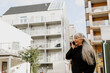© Johnér - Senior woman talking on cell phone in front of building