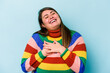 Young caucasian overweight woman isolated on blue background laughing keeping hands on heart, concept of happiness.