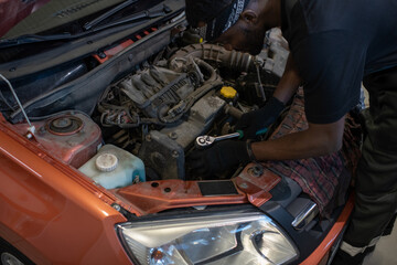 Wall Mural - High angle view at black car mechanic holding wrench while repairing engine in auto workshop, copy space