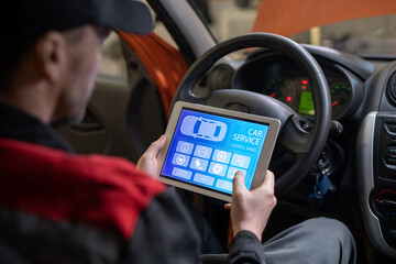 Wall Mural - Close up of car mechanic using digital tablet with service and maintenance app on screen while inspecting vehicle in auto repair shop